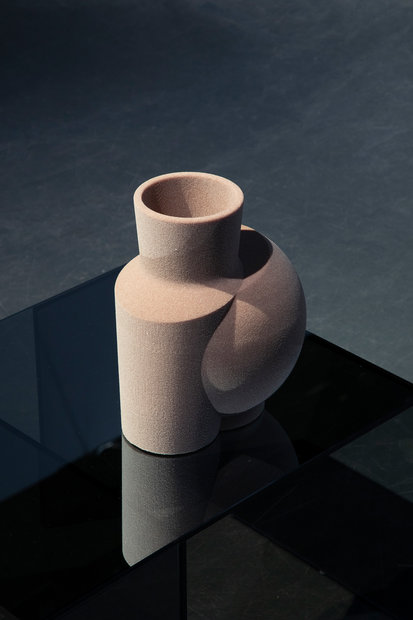 Die Vase wird digital in all ihre Ebenen und Bestandteile zerlegt. Materialität, genauso wie Größe und Form, sind nunmehr variabel. Sie muss keiner Funktion gerecht werden. Durch die Übertragung zurück ins Analoge, kommen den einzelnen Ebenen neue Funktionen zu: Die Textur wird zum Material, aus dem die Vase besteht. Es entsteht eine analog-digitale Skulptur, eine Collage aus Körper und Fläche – ein Hybrid aus Bild und Objekt. Die Collage eröffnet einen Zwischenraum(f), in dem sich die Vase in ihrem transformierten Äußeren präsentiert, lediglich die Reflexion lässt sie in ihrer ursprünglichen Form erscheinen. Es werden so Qualitäten aus beiden Welten verflochten. Die Skulptur findet Platz auf einem Sockel aus Glas, von dem sie getragen, jedoch nicht mehr verdeckt wird.